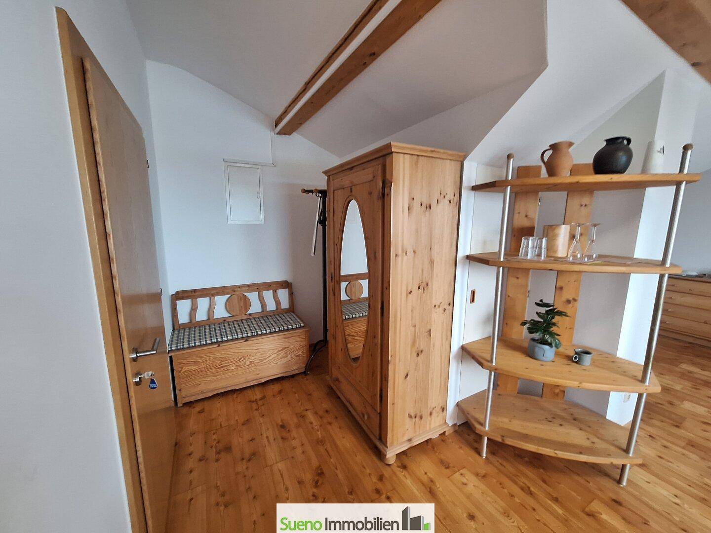 Flur mit rustikalen Holzmöbeln, Holzboden und sichtbaren Deckenbalken.