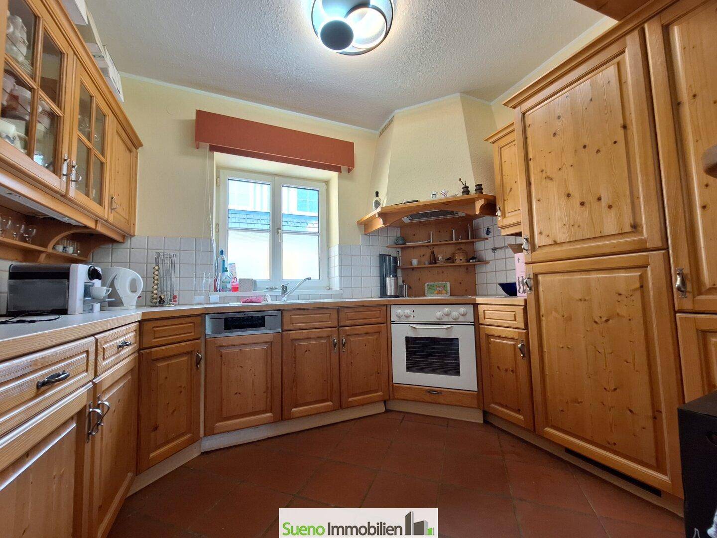Traditionelle Küche mit Holzschränken, Einbaugeräten und Fenster über der Spüle.