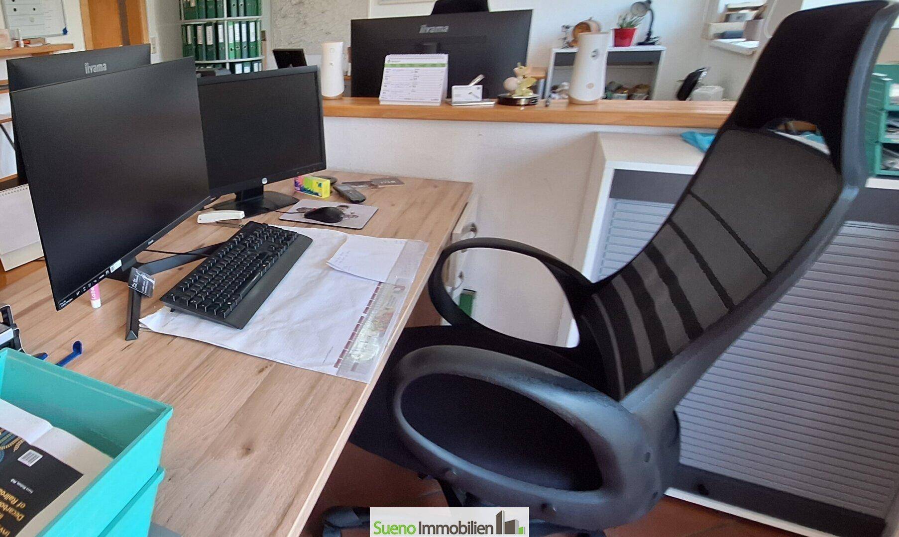 Detailansicht eines modernen Arbeitsplatzes im Büro mit Computerbildschirm und Bürostuhl.