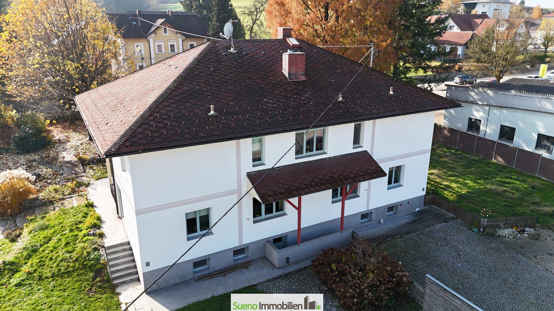 Rückansicht des Hauses mit überdachtem Eingangsbereich und gepflegter Fassade in ländlicher Umgebung.