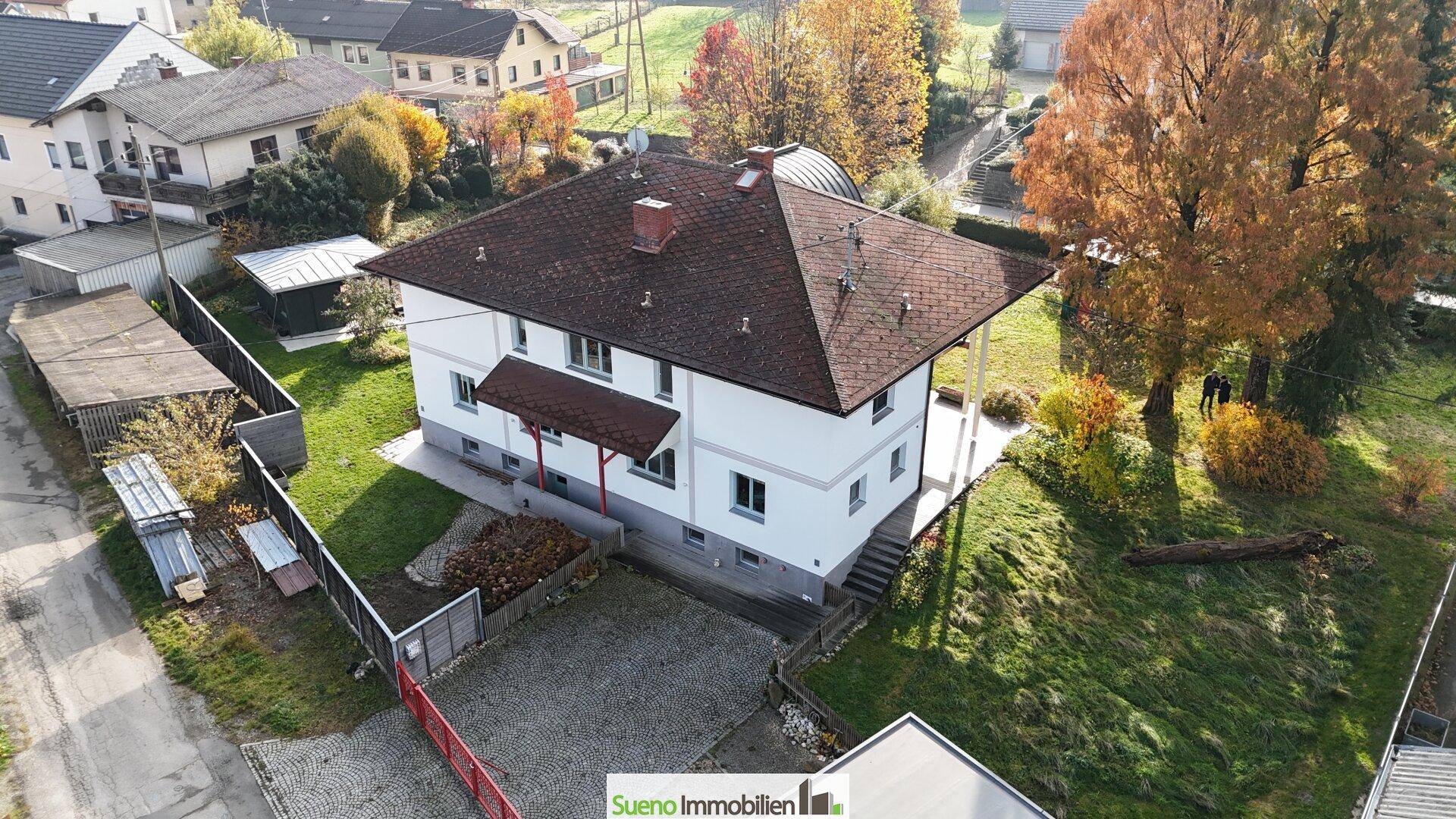 Luftaufnahme der Rückseite des Hauses mit Garten, Zufahrt und angrenzenden Grundstücken.