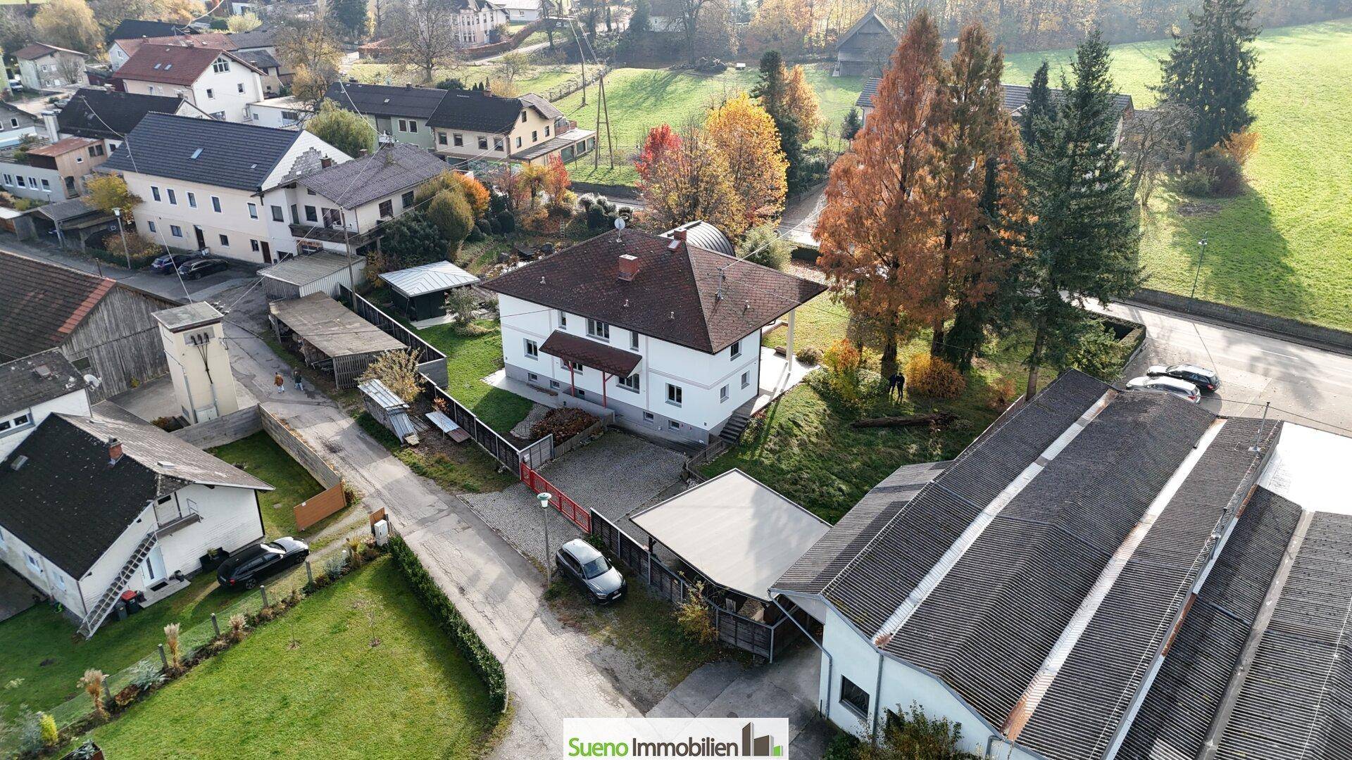 Luftaufnahme eines Wohnhauses mit umliegenden Gebäuden und Grünflächen.