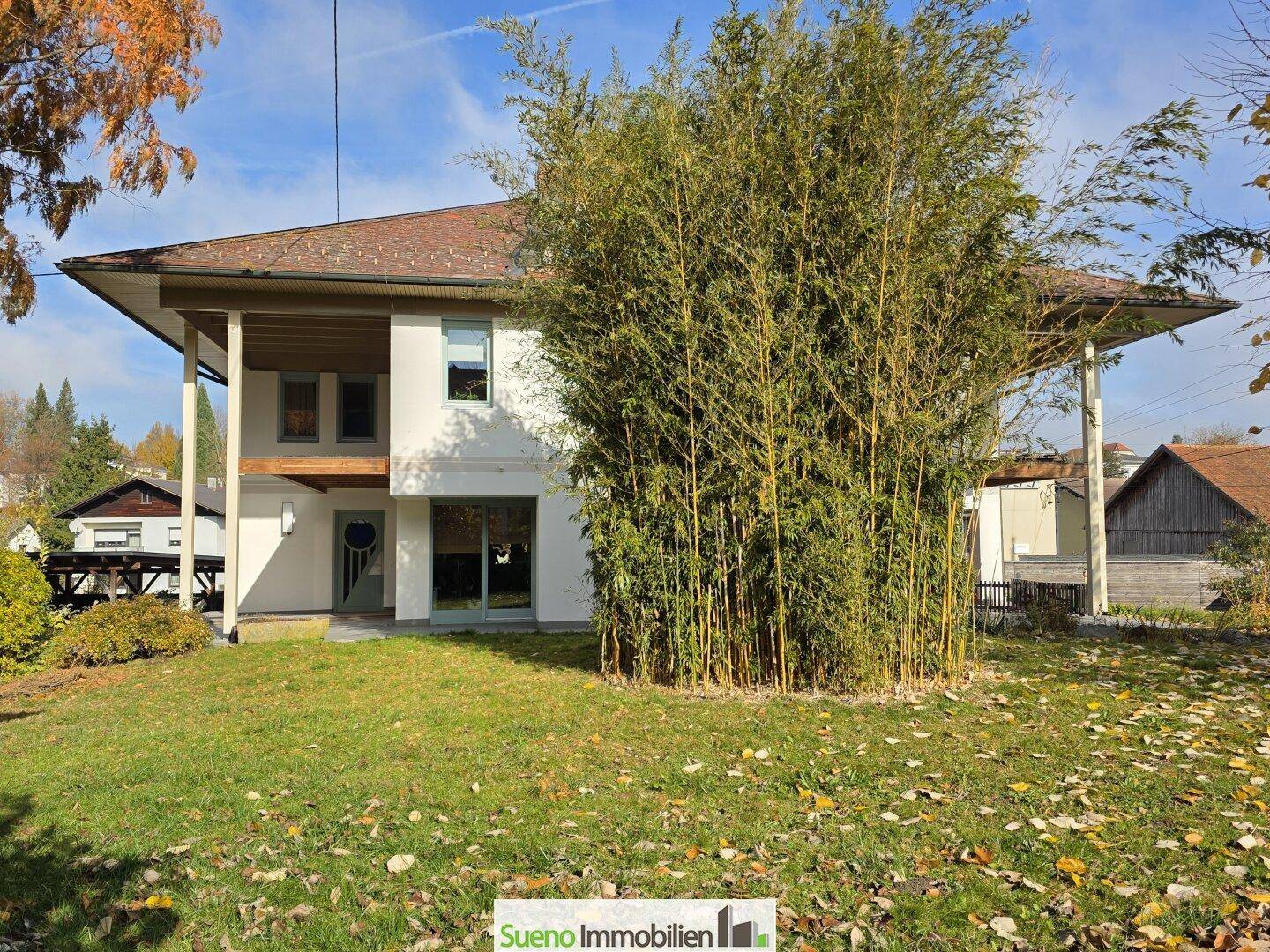 Rückseite des Hauses mit gepflegtem Rasen und hohen Bambuspflanzen, die Privatsphäre bieten.
