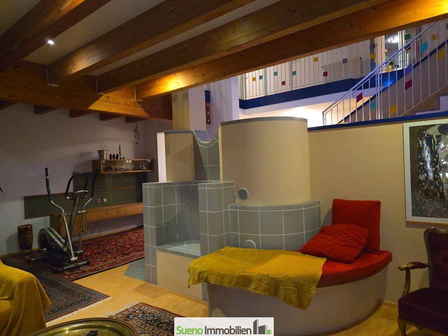 Geräumiges Wohnzimmer mit traditionellem Kachelofen, Holzbalkendecke und farbenfroher Einrichtung.