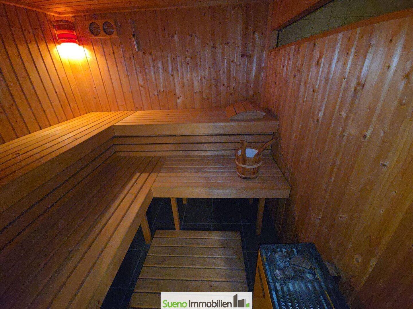 Traditionelle Holzsauna mit Bänken und Saunaofen für Entspannung.