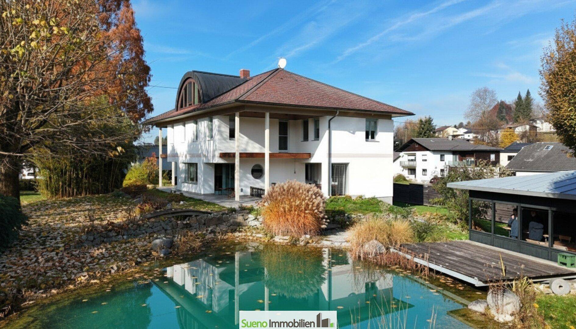 Charmantes Einfamilienhaus mit großem Garten, Schwimmteich und viel Grünfläche an einem sonnigen Tag.