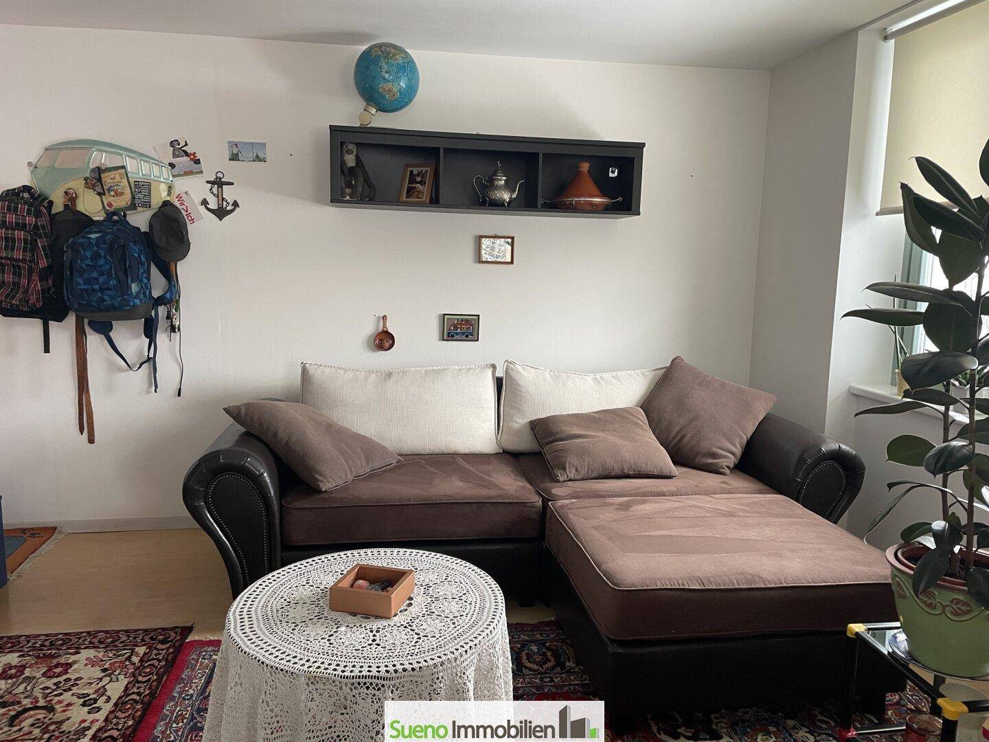 Gemütliches Wohnzimmer mit braunem Sofa, Teppich und Wanddekoration.