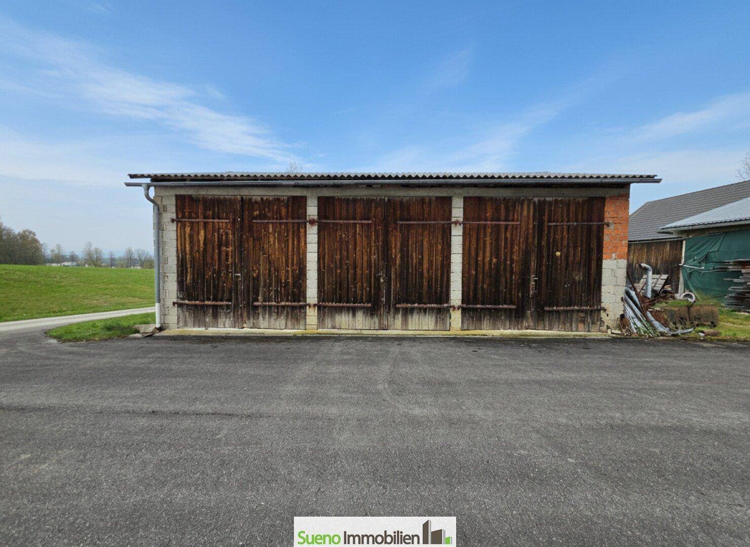 Lange Garagenreihe mit Holztoren und einfacher Bauweise auf dem Grundstück.