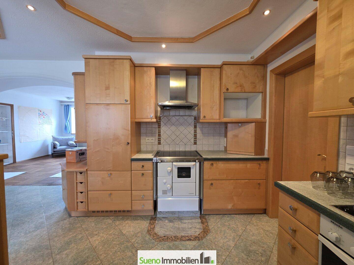 Gemütliche Holzküche mit traditionellen Schränken, Fliesenrückwand und integriertem Herd.