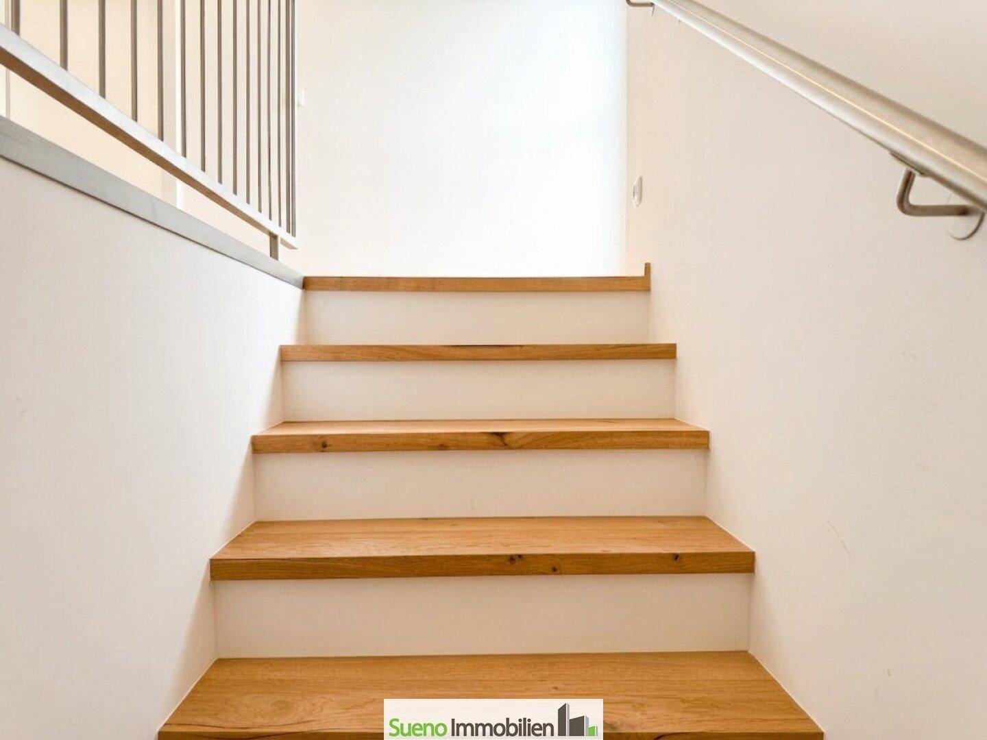 Moderne Holztreppe mit Metallgeländer, die zu den oberen Etagen führt.