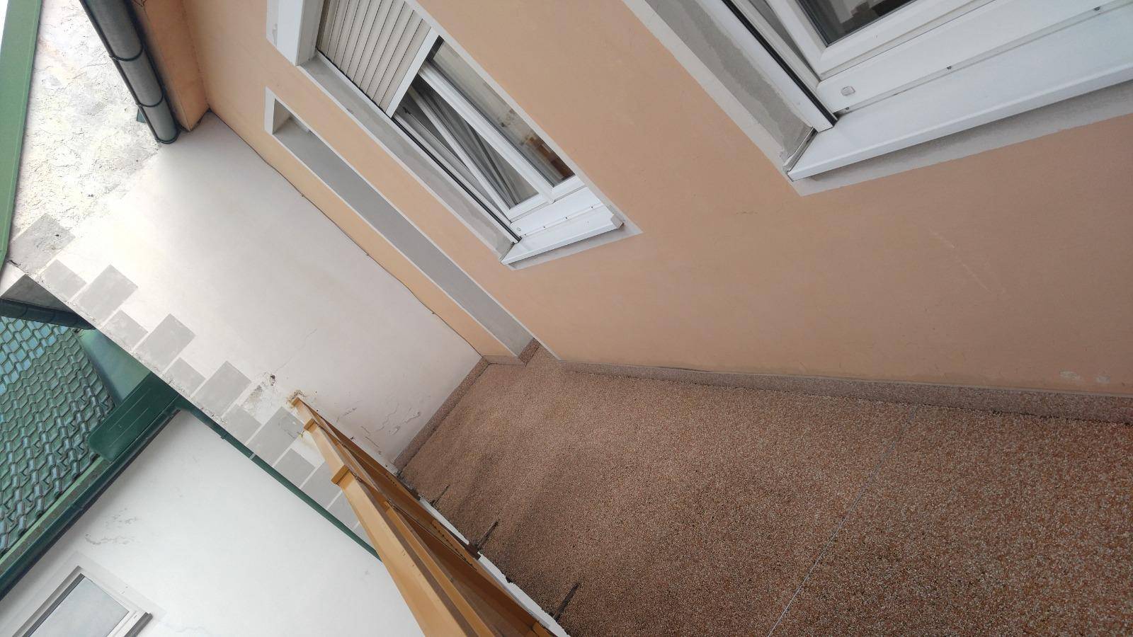 Kleiner Balkon mit Kiesboden und Fenster mit Rollladen, bietet einen privaten Außenbereich.