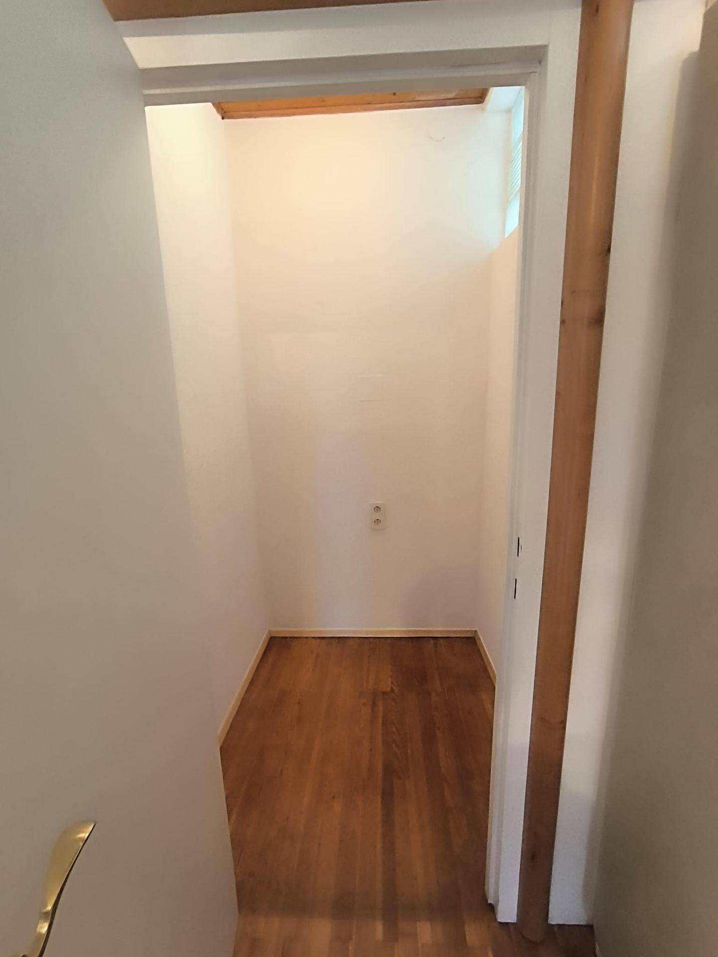 Kleiner, leerer Abstellraum mit Holzplankenboden und weißen Wänden, ideal für zusätzlichen Stauraum.