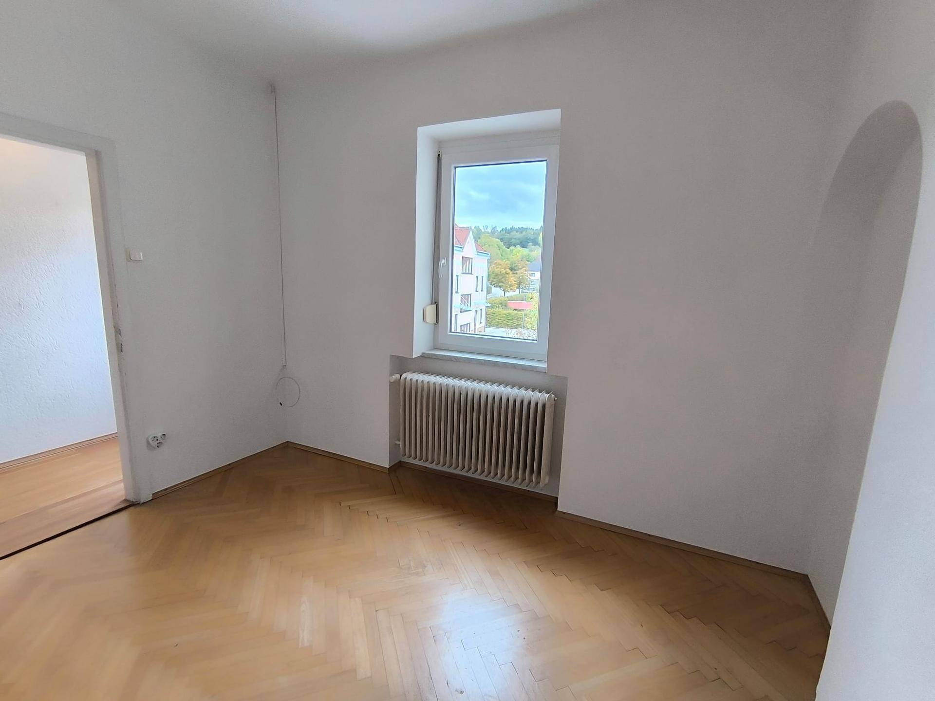 Geräumiges Zimmer mit Parkettboden und einem Fenster, ideal als Schlaf- oder Arbeitszimmer.
