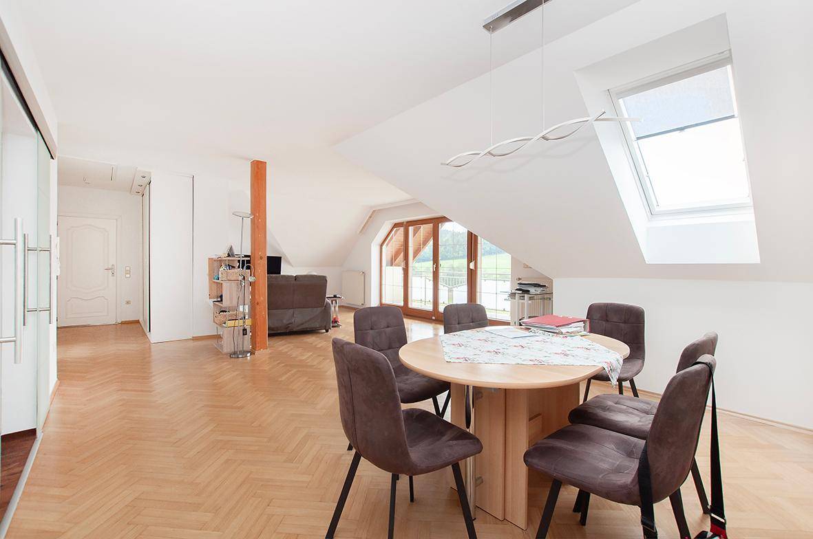 Gemütlicher Essbereich im offenen Wohnraum mit Dachfenster und Holzbalken.