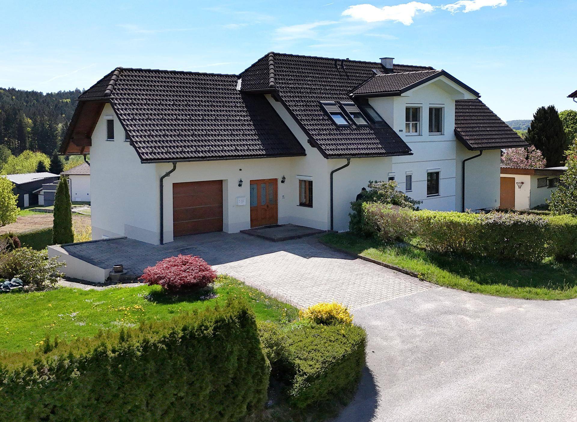 Rückansicht des Einfamilienhauses mit Doppelgarage, gepflasterter Auffahrt und gepflegtem Vorgarten.