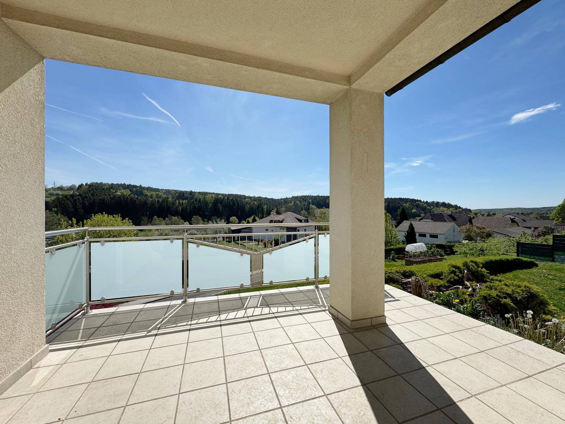 Überdachte Loggia mit Fliesenboden und Panoramablick auf die umliegende Natur.