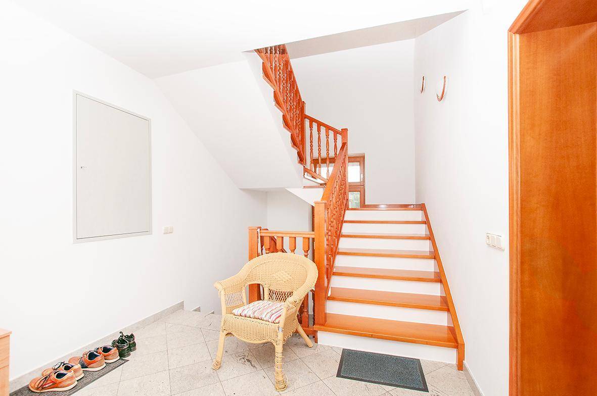 Eingangsbereich mit Holztreppe, Fliesenboden und heller Wandgestaltung.