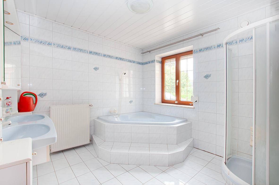 Geräumiges Badezimmer mit Eckbadewanne, Dusche, Doppelwaschbecken und Fenster.
