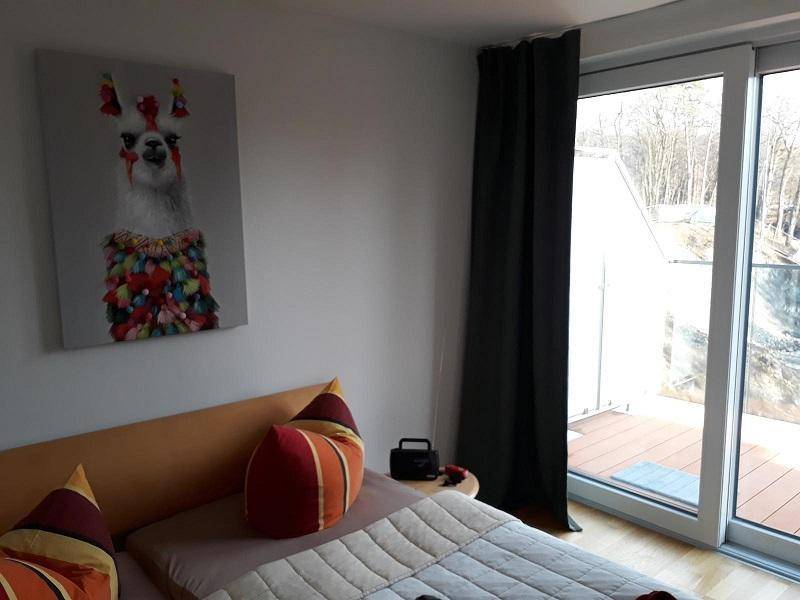 Gemütliches Schlafzimmer mit Holzboden, farbenfroher Dekoration und direktem Zugang zu einem sonnigen Balkon.