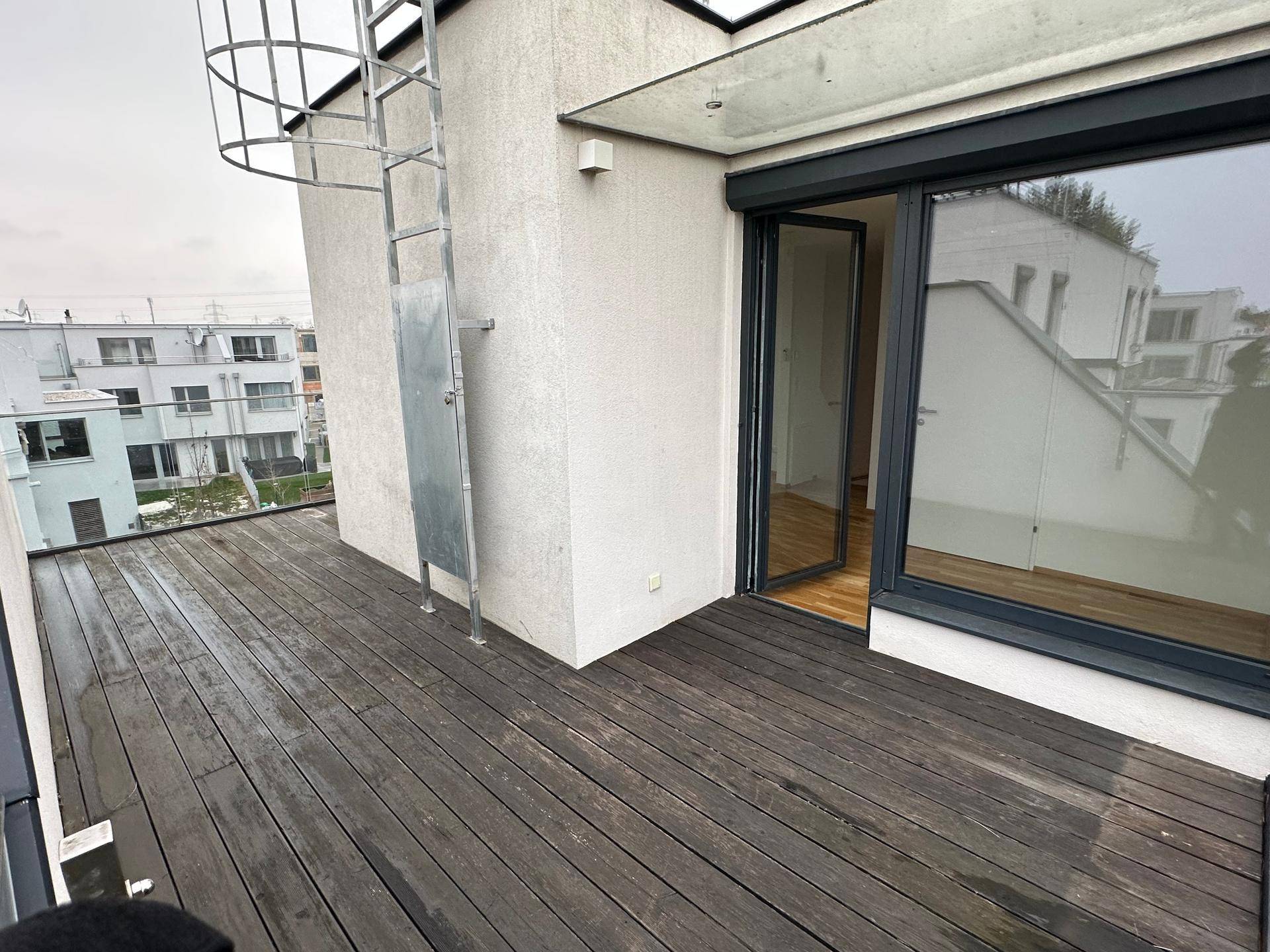 Geräumige Dachterrasse mit Holzbelag und Blick auf die umliegenden Gebäude.