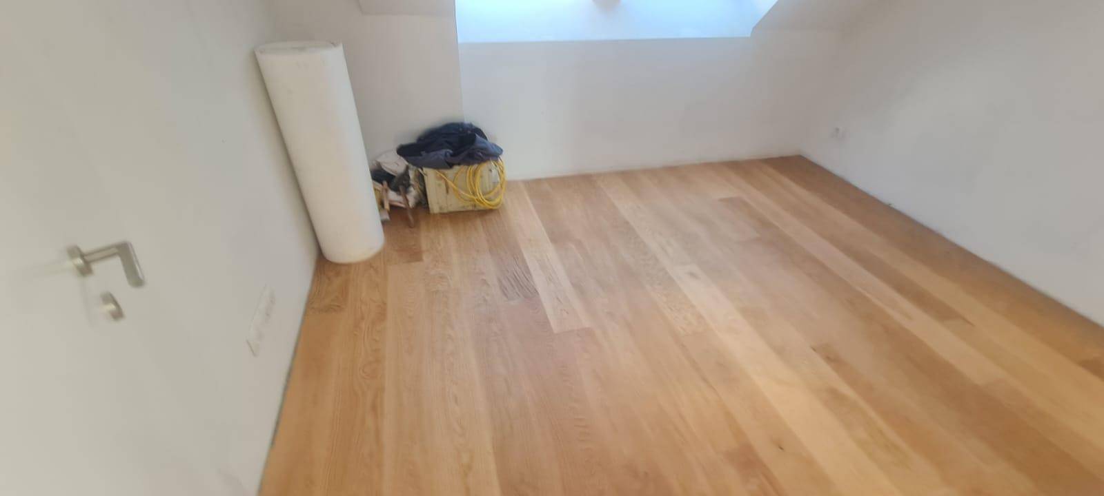 Leerer Raum im Dachgeschoss mit Holzboden und schrägen Wänden, bereit für die Einrichtung.