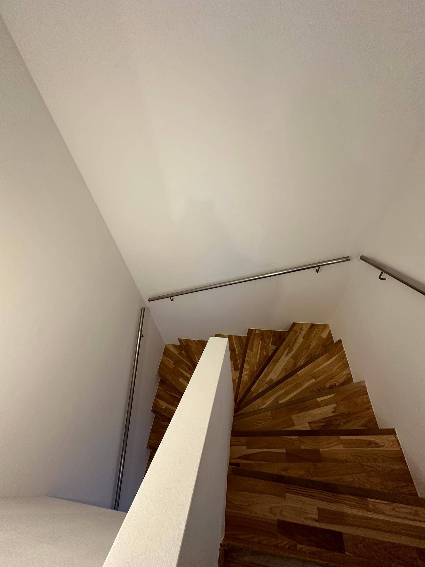 Elegante Holztreppe mit Edelstahlgeländer, die die verschiedenen Etagen verbindet.