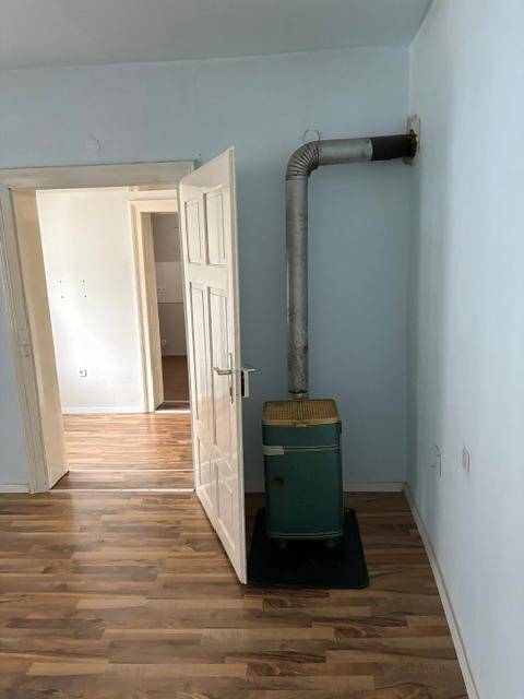 Wohnraum mit einem grünen Holzofen, blauen Wänden und Laminatboden, der Gemütlichkeit verspricht.