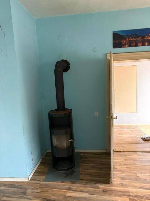 Wohnraum mit einem Holzofen, blauen Wänden und Laminatboden, der Wärme spendet.