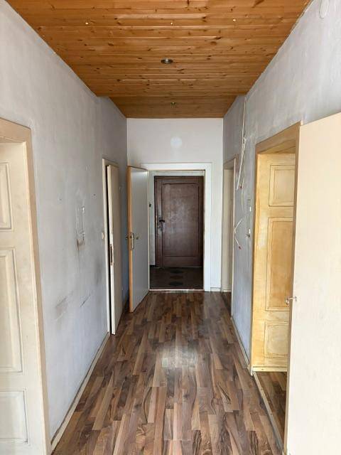 Langer Flur mit Holzdeckenverkleidung und Laminatboden, der zu weiteren Räumen führt.