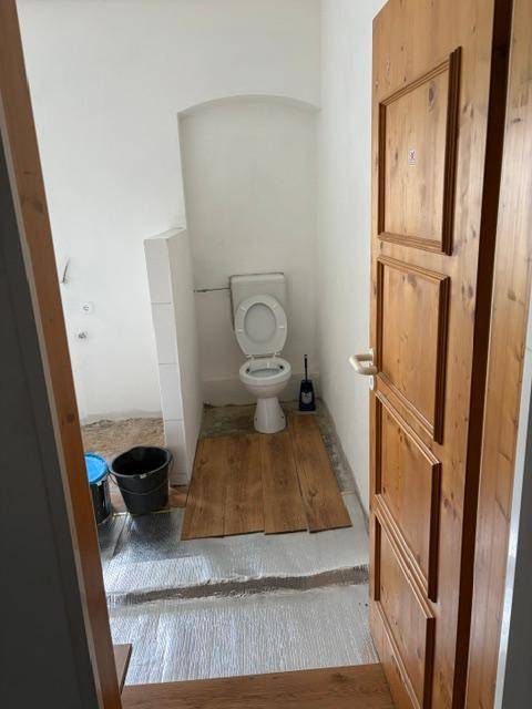 WC-Raum im Umbau mit installierter Toilette und vorbereitetem Boden, bereit für die Fertigstellung.