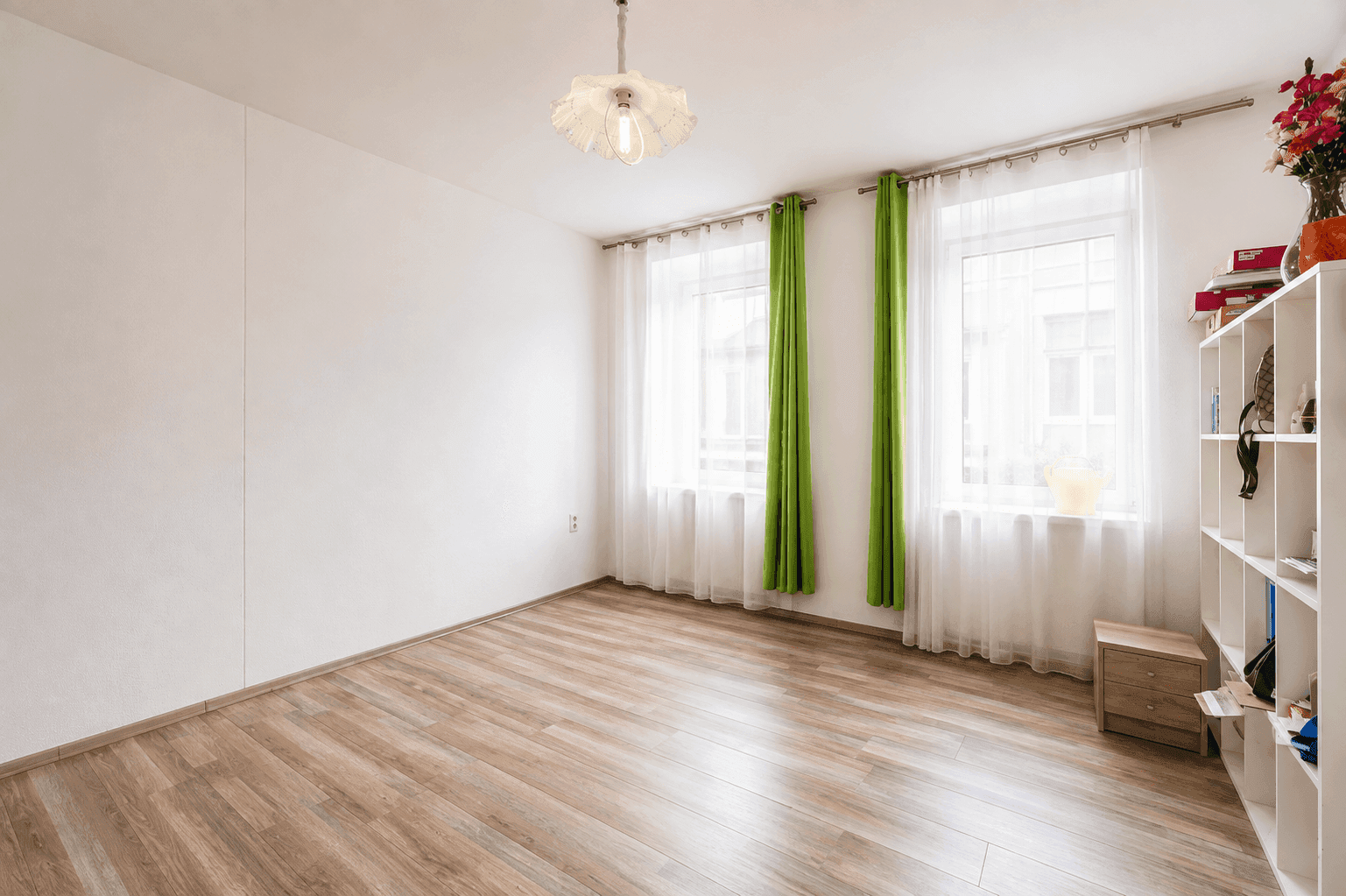 Helles, unmöbliertes Zimmer mit Laminatboden und zwei Fenstern, bereit zur individuellen Gestaltung.