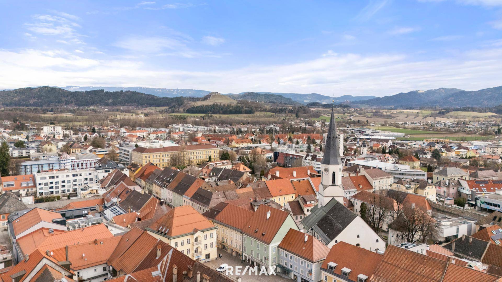 Panoramablick über eine historische Stadt mit roten Dächern und umliegender Landschaft.