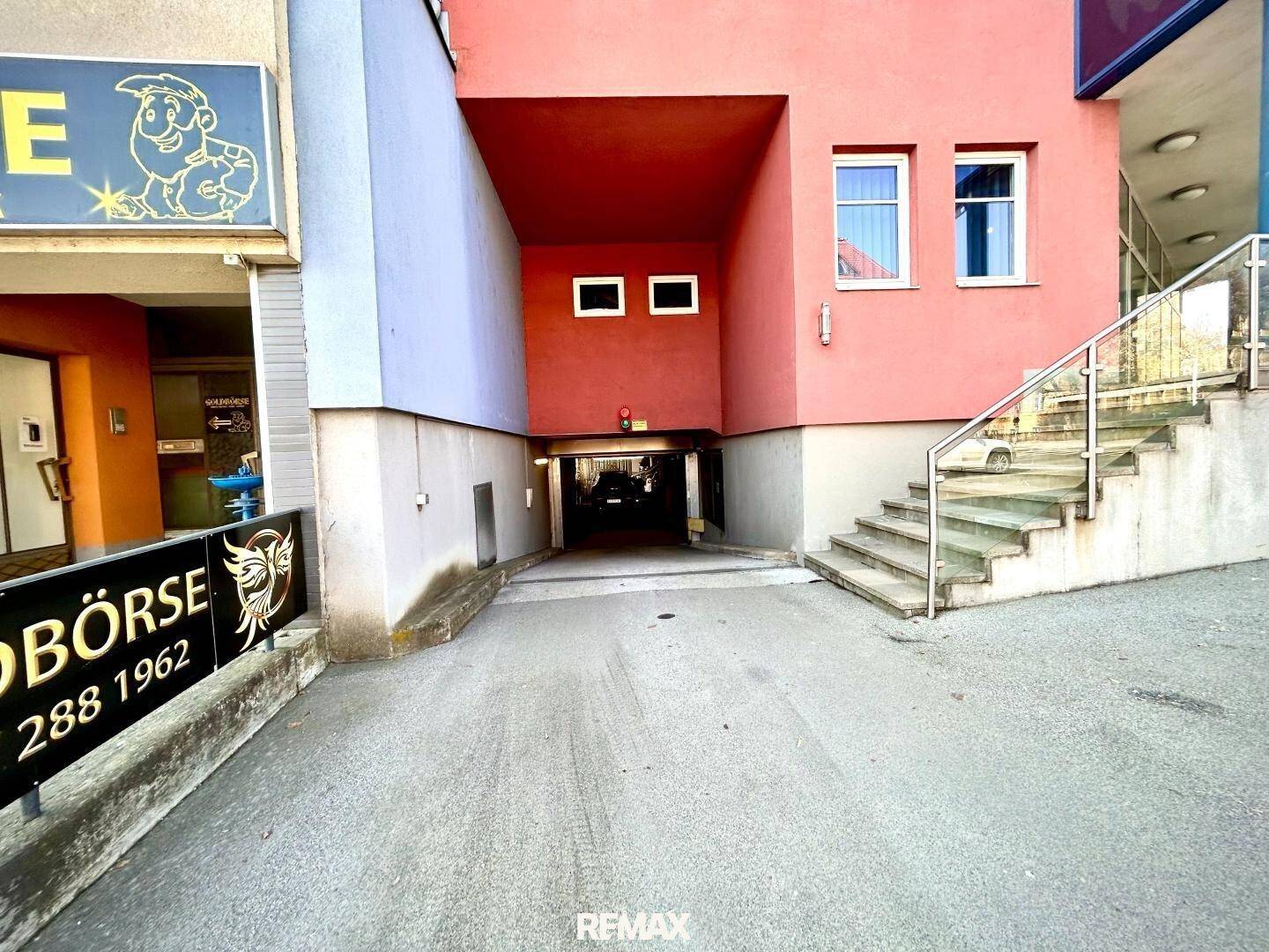Zufahrt zu einer Tiefgarage mit angrenzender Treppe und Teil der Gebäudefassade.