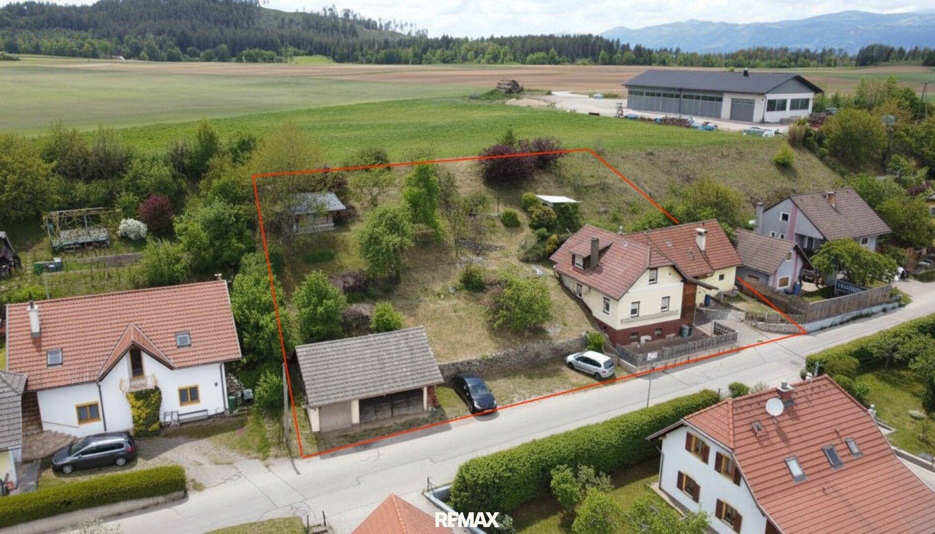 Luftaufnahme des Hauses mit großem, leicht geneigtem Grundstück und Blick auf die umliegende Landschaft.