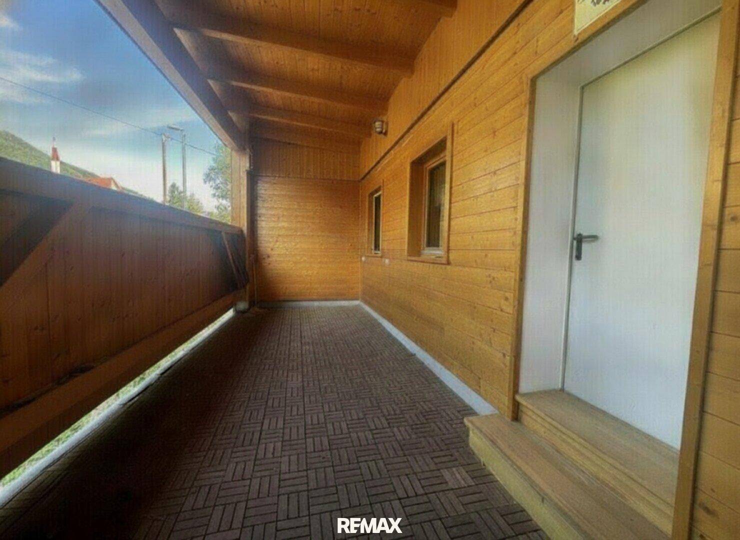 Überdachter Außenbereich mit Holzwänden, Holzbalkendecke und einem gefliesten Boden, ideal zum Entspannen.
