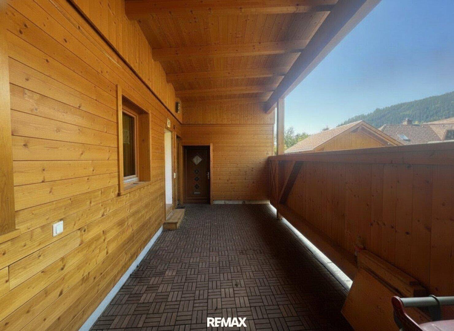 Geräumige überdachte Loggia mit Holzausstattung und Fliesenboden, bietet einen geschützten Außenbereich.