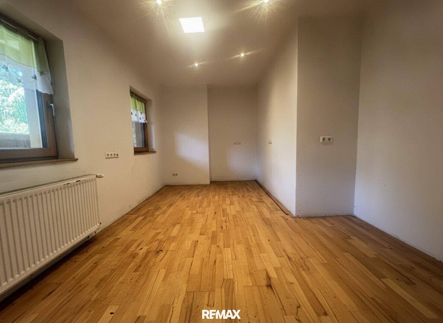 Heller Raum mit Holzfußboden, weißen Wänden, zwei Fenstern und Deckenstrahlern, bietet vielseitige Nutzungsmöglichkeiten.