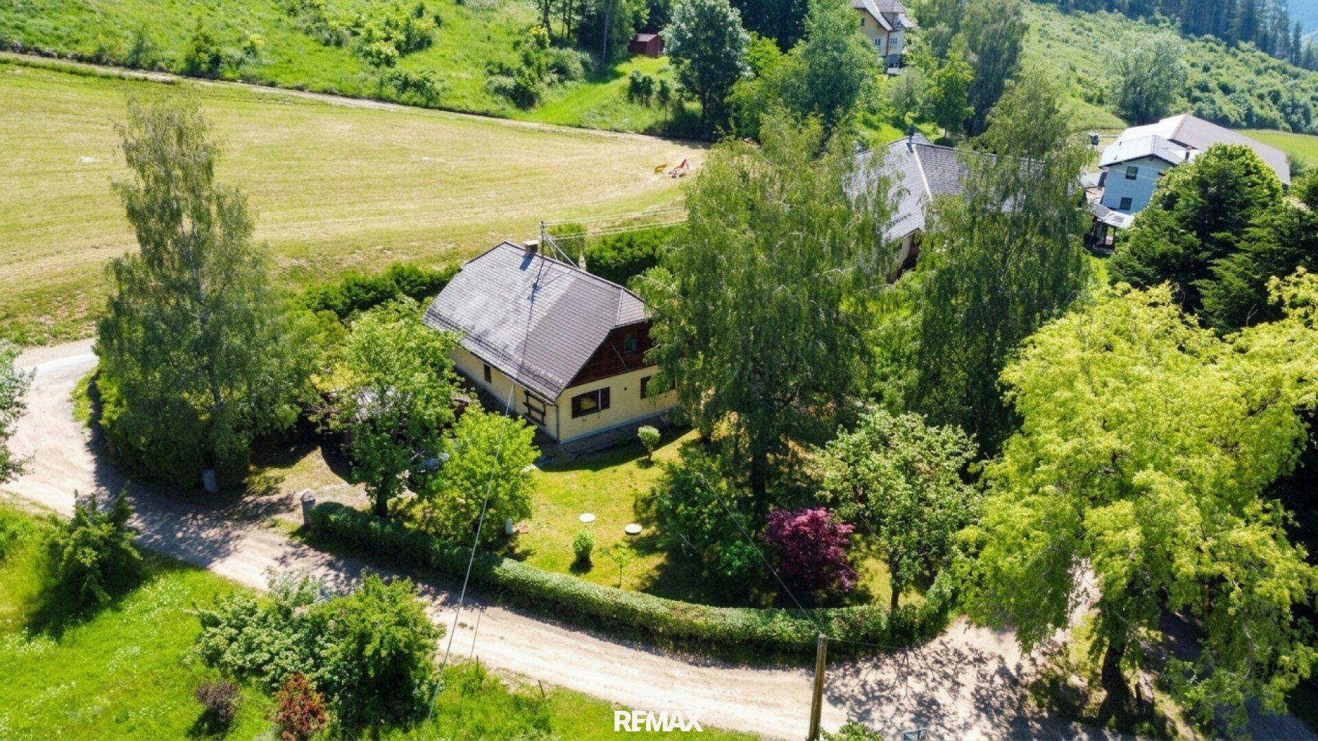 Luftaufnahme eines Hauses mit Garten, umgeben von grünen Feldern und Bäumen.
