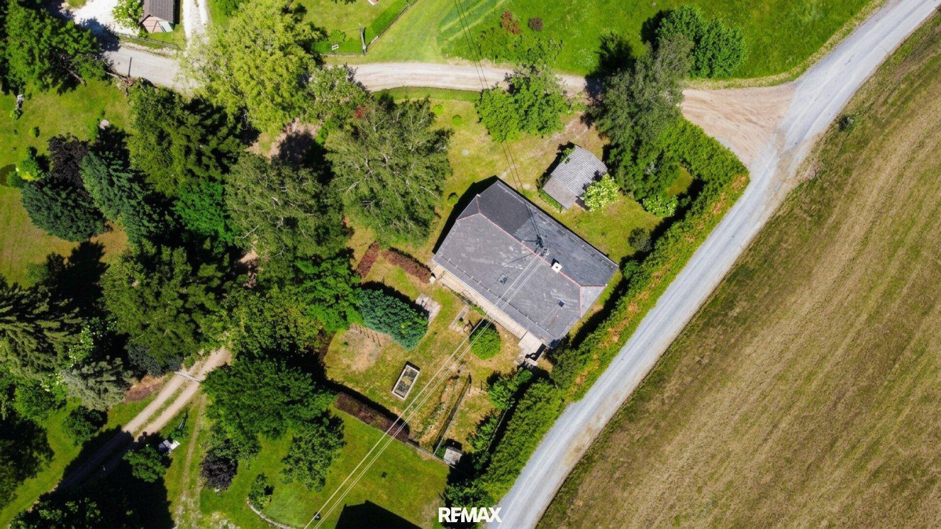 Senkrechte Luftaufnahme eines Hauses mit Garten, umgeben von Feldern und Wegen.