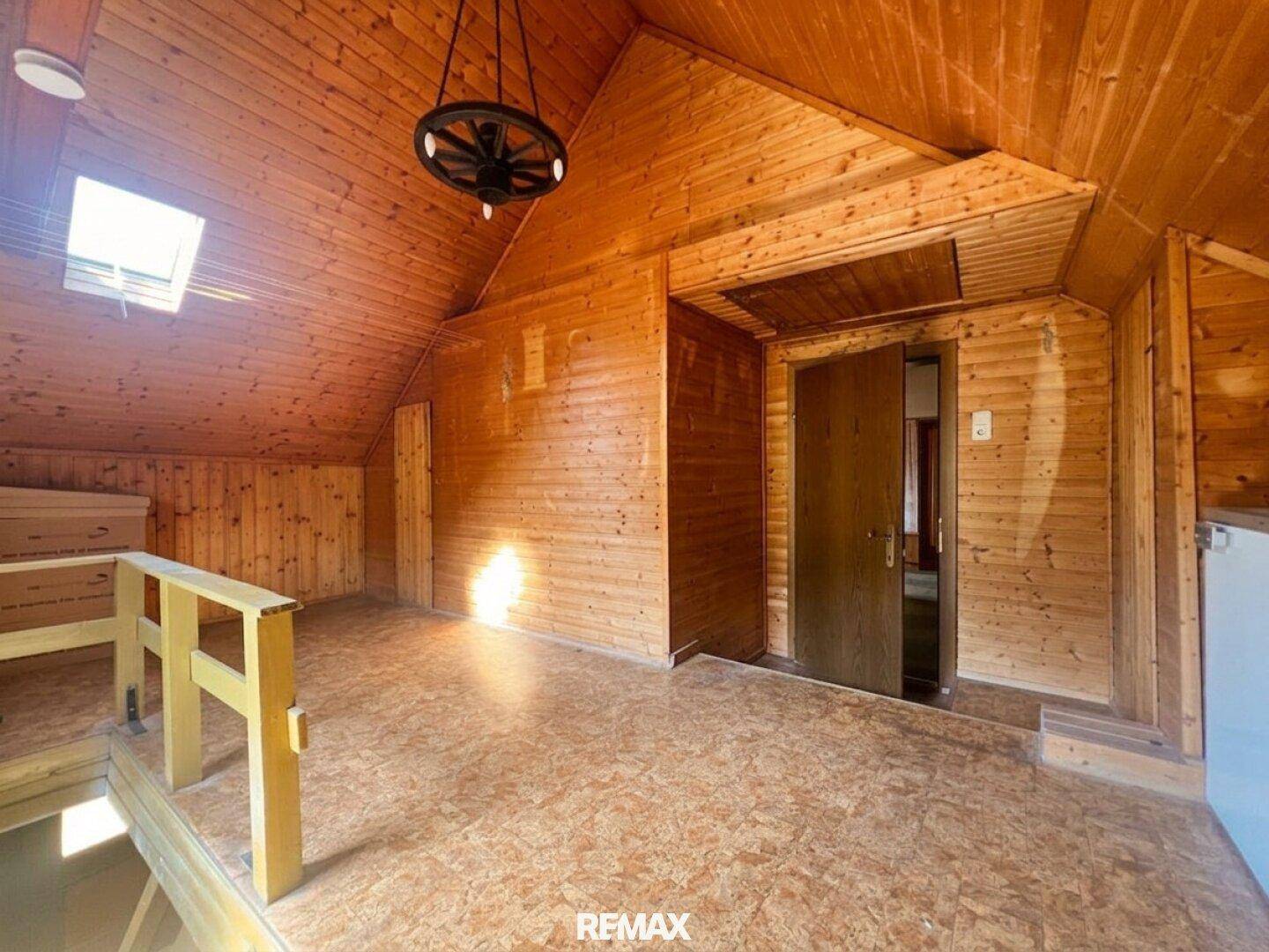 Gemütlicher Dachbodenraum mit vollständiger Holzverkleidung, Dachfenster und rustikalem Charme.