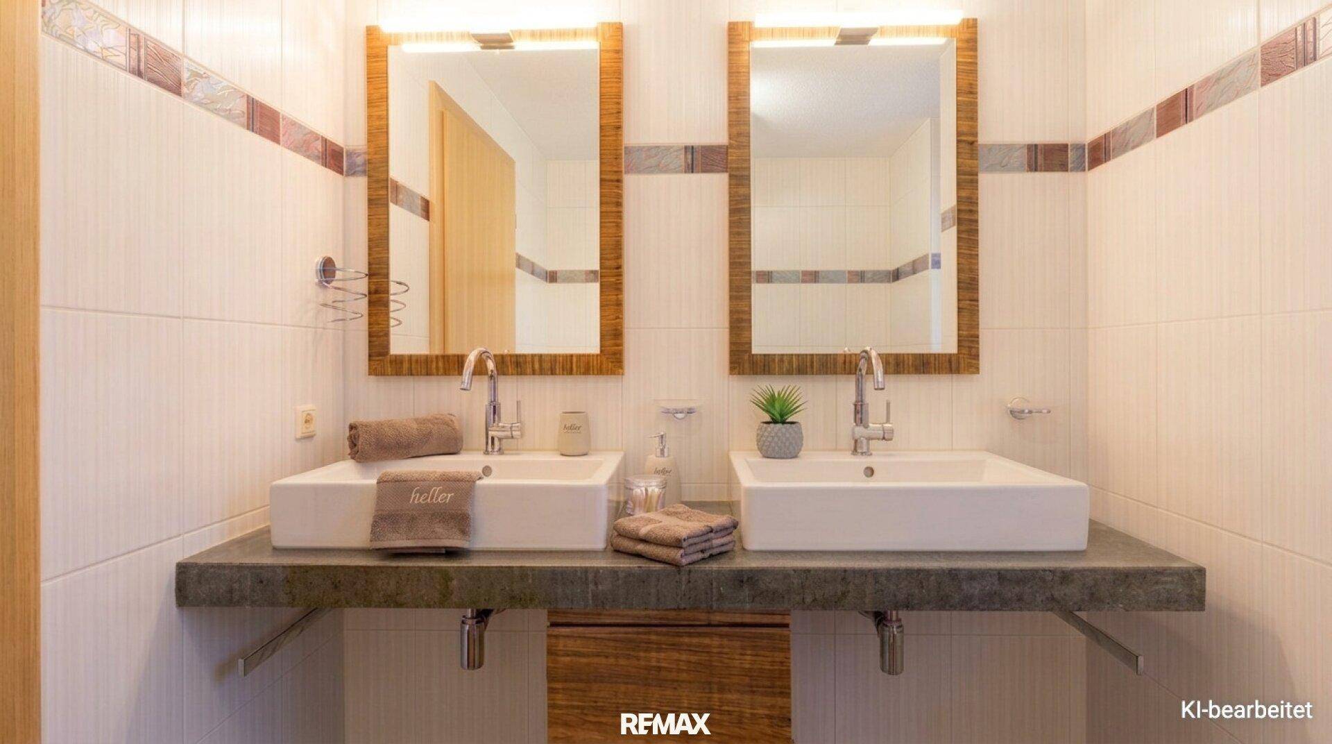 Badezimmer mit zwei modernen Waschbecken, großen Spiegeln und hellen Fliesen.