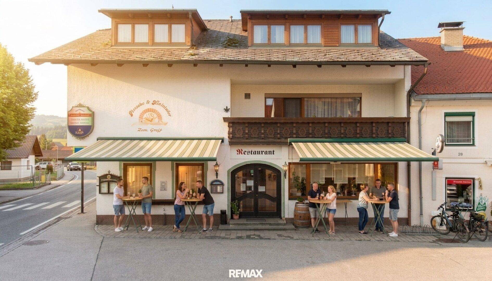 Frontansicht des Gasthauses mit Restaurant, Markisen und Gästen im Außenbereich.