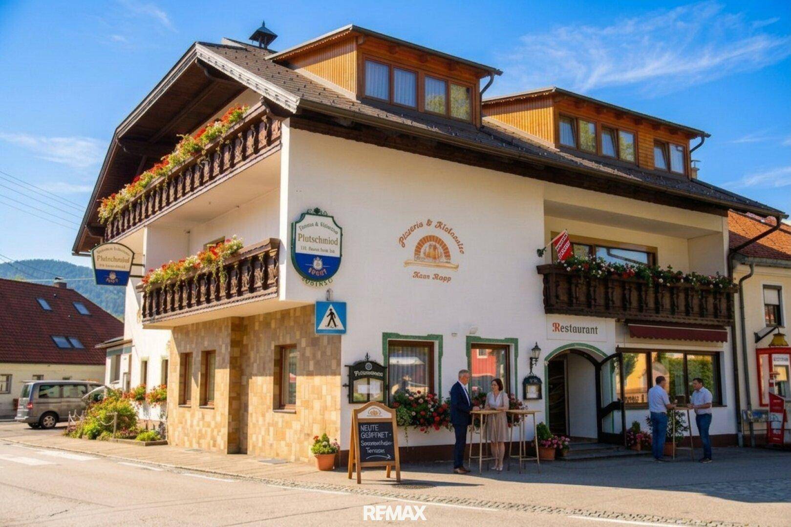 Seitenansicht des Gasthauses mit Restaurant, Balkonen und traditionellen Holzelementen.