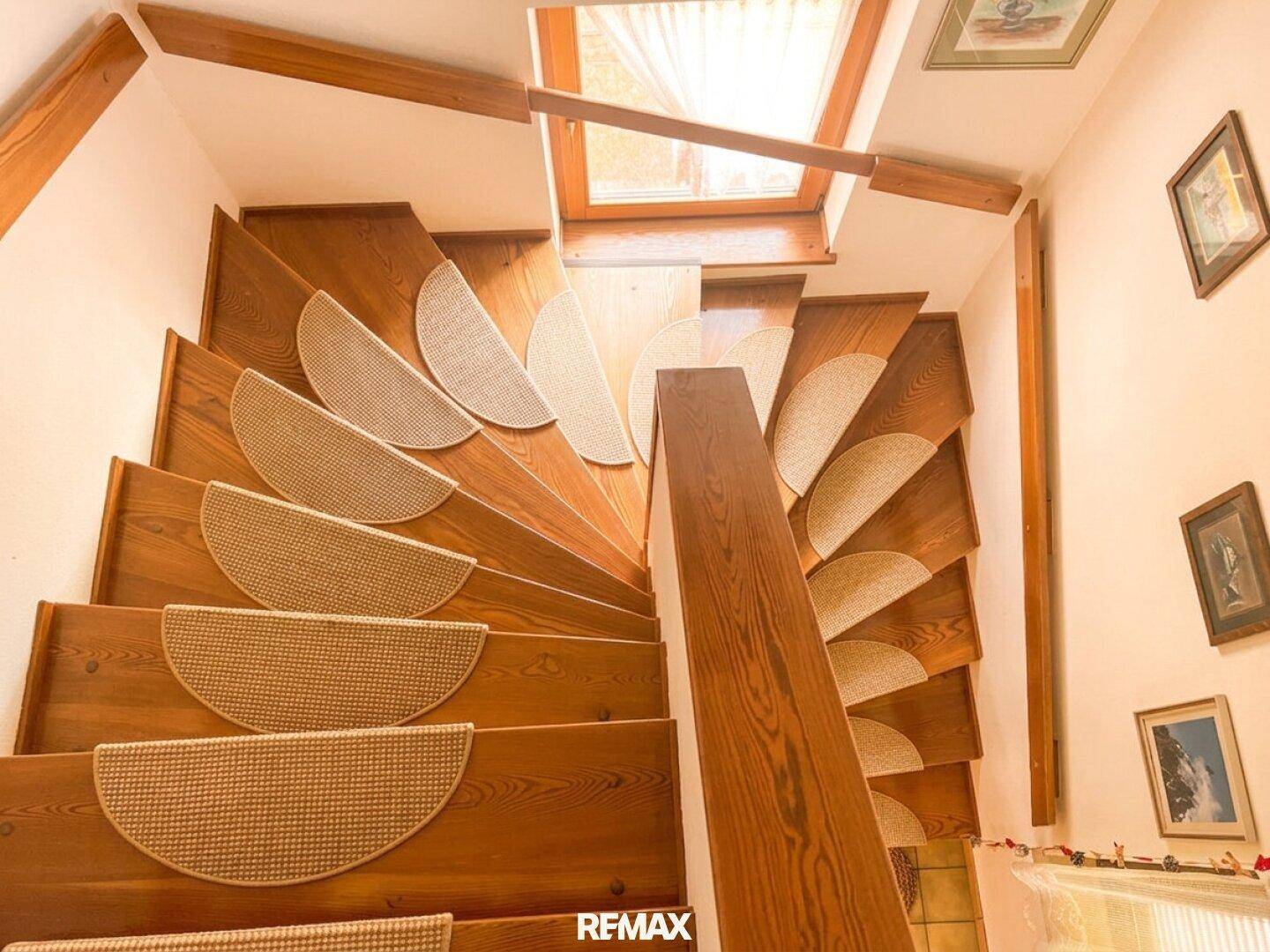 Holztreppe mit Teppichstufen und einem Oberlicht, das natürliches Licht spendet.
