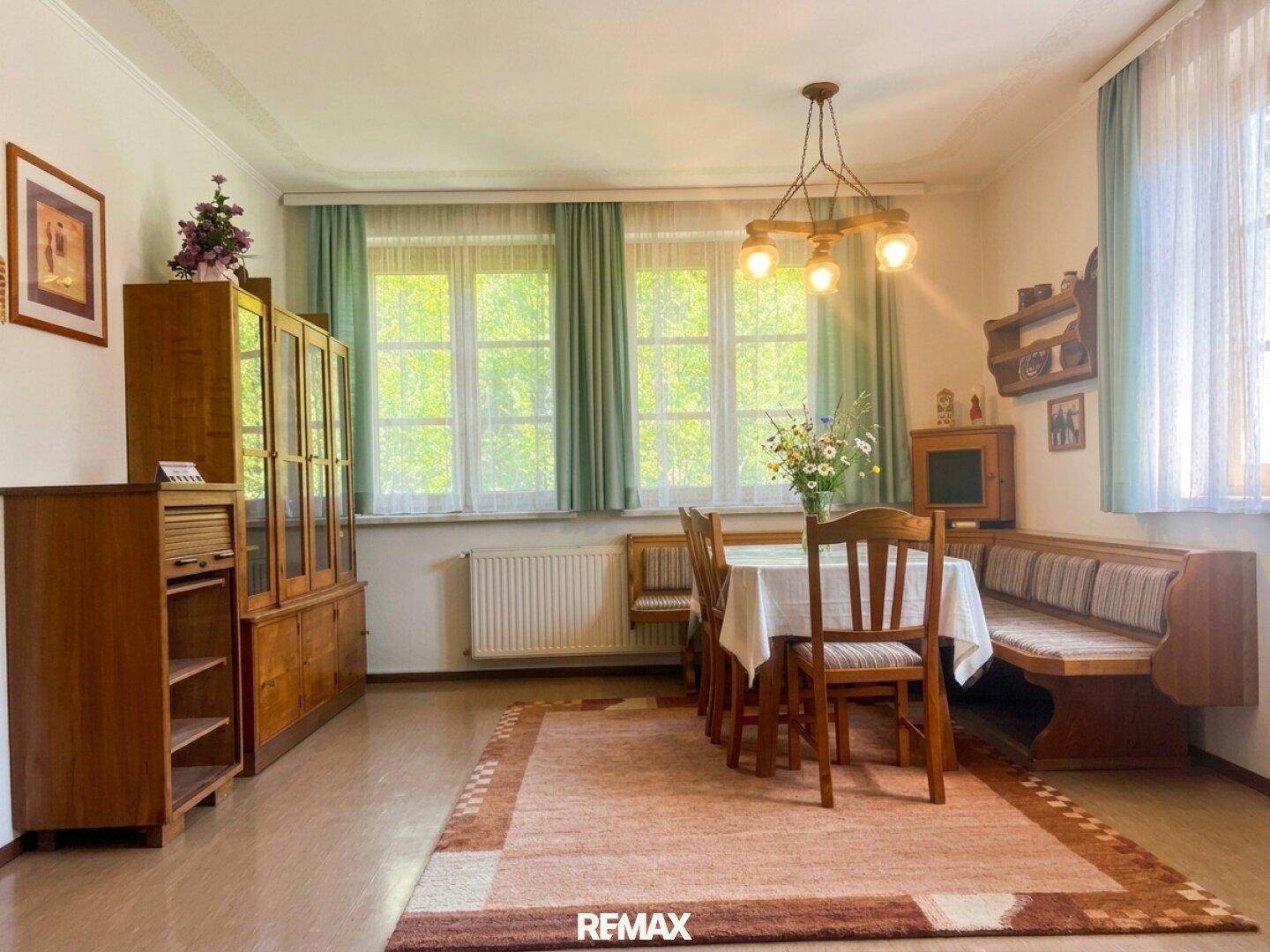 Essbereich mit Holztisch, Stühlen, eingebauter Bank und einem großen Holzschrank.