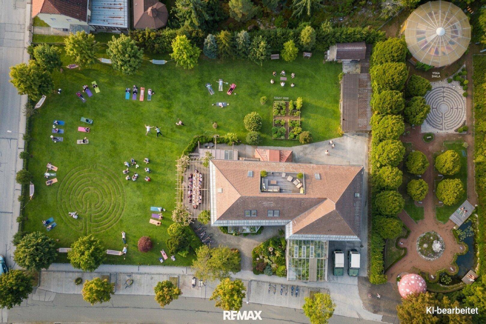 Luftaufnahme eines Anwesens mit großem Garten, Rasenflächen und einem modernen Hauptgebäude.