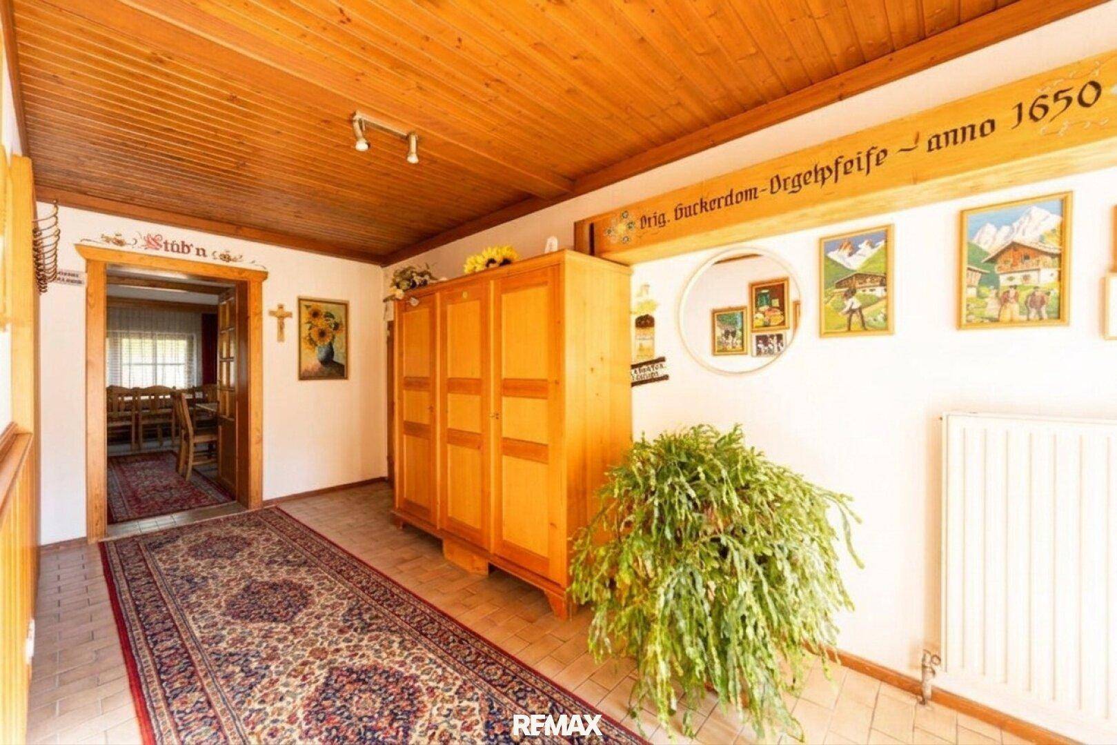 Traditioneller Flur mit Holzbalkendecke, rustikalen Möbeln und einem gemusterten Teppich.