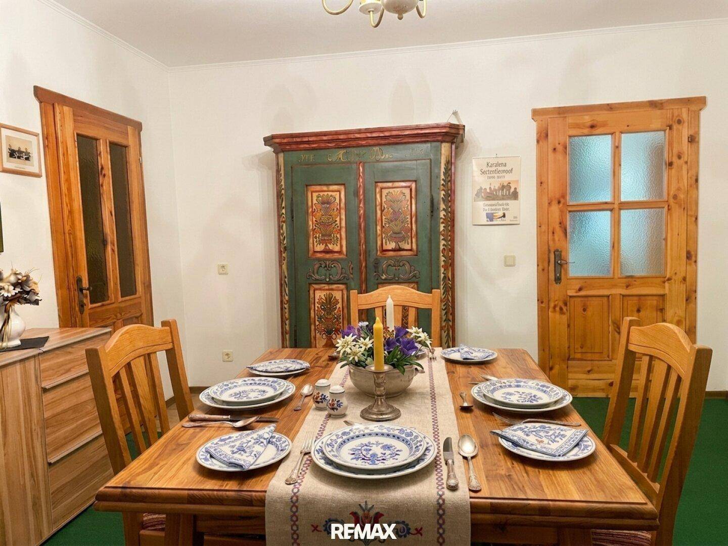Gemütlicher Essbereich mit gedecktem Holztisch, traditionellem Schrank und Holztüren.
