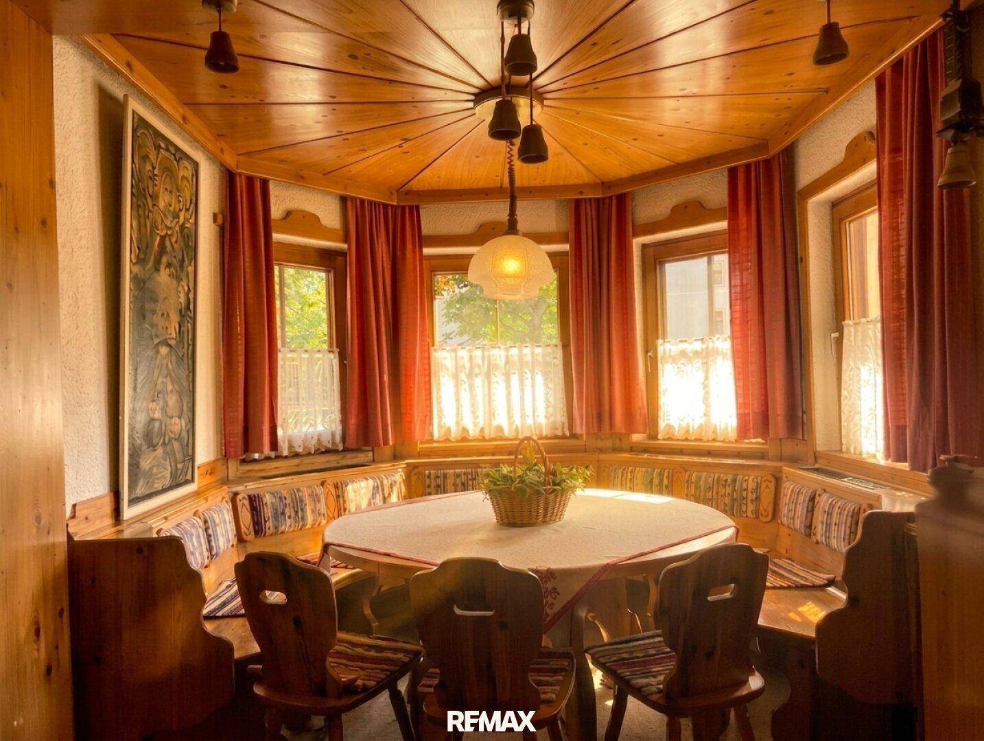 Gemütliche Essecke mit runder Tafel, eingebauten Bänken und viel Tageslicht durch die Fenster.