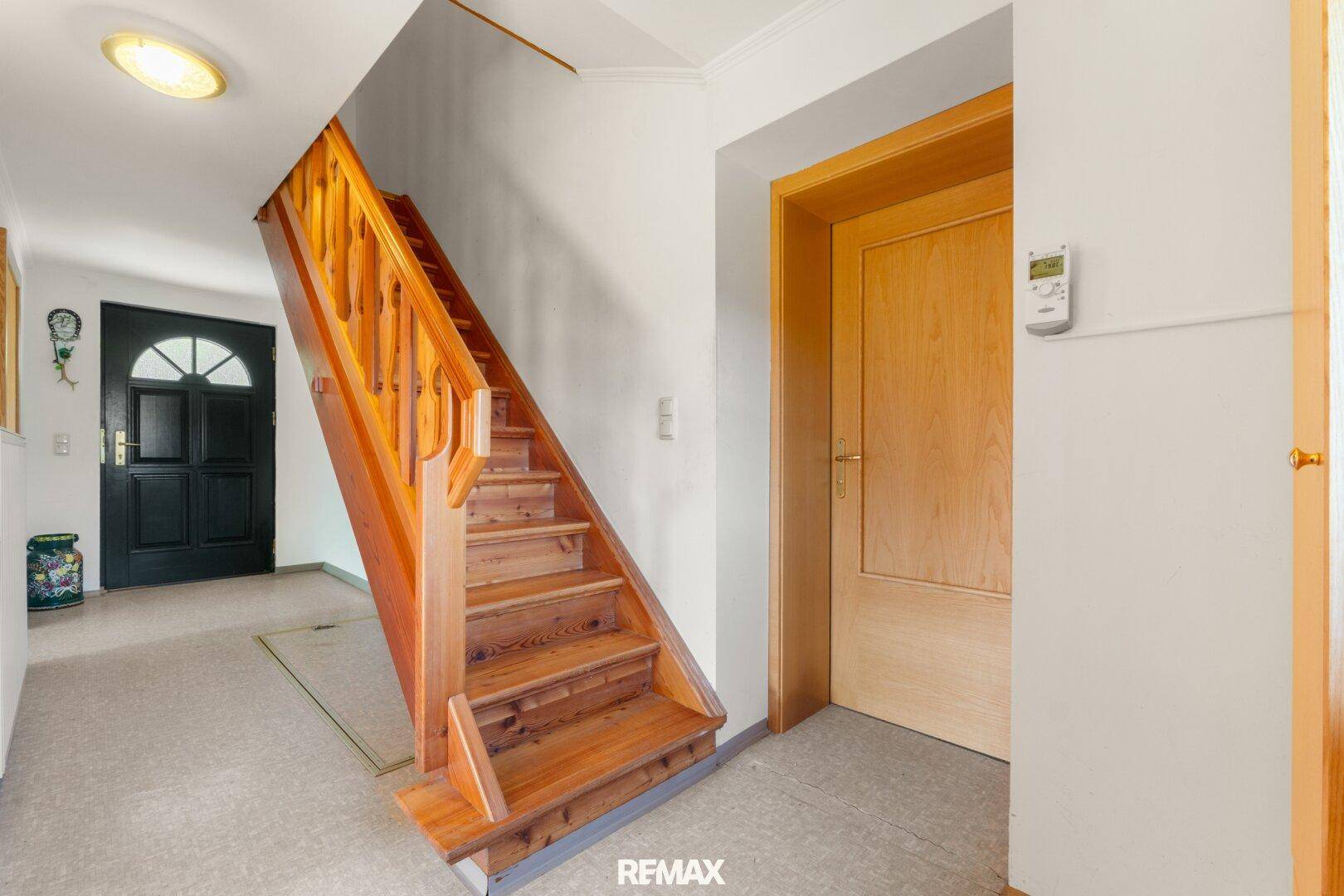 Heller Flur mit einer traditionellen Holztreppe, die in die obere Etage führt.